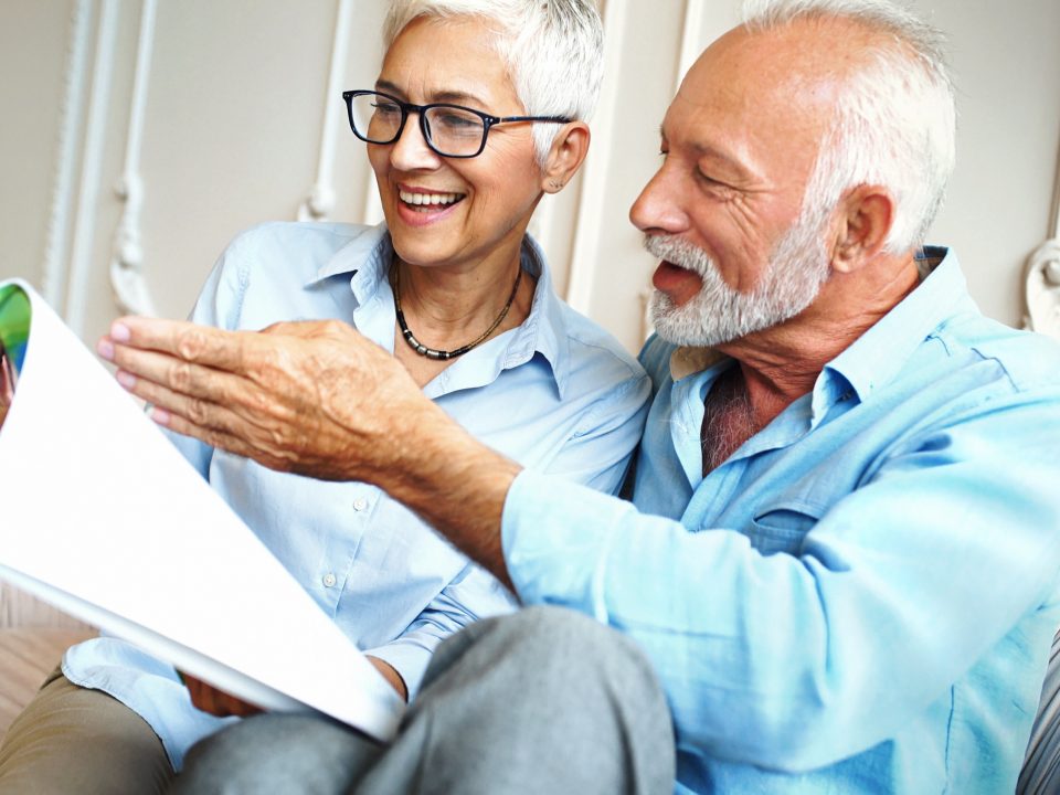 Closeup side view view of a cheerful senior couple relaxing in living room and reading